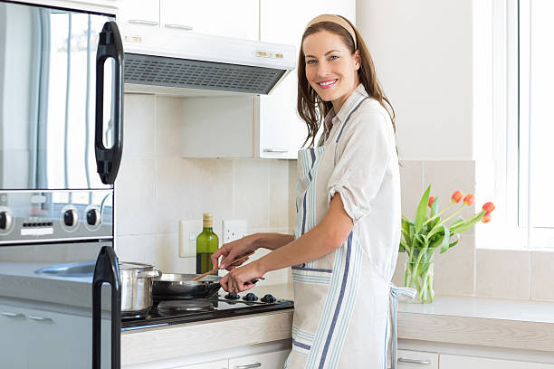 istock Smiling young woman preparing food in kitchen 464863904
