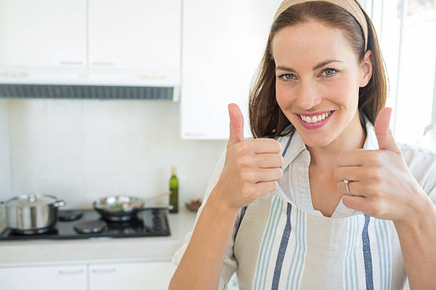 istock Smiling young woman gesturing thumbs up in kitchen 464863992