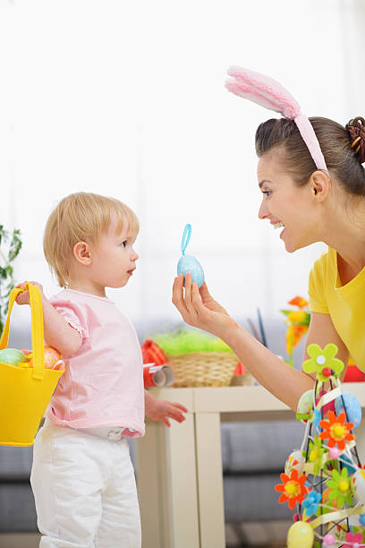 istock mother helping baby collecting easter eggs 464864928