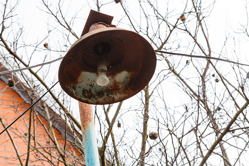 rusty lantern with electric light bulb at village backyard in spring day