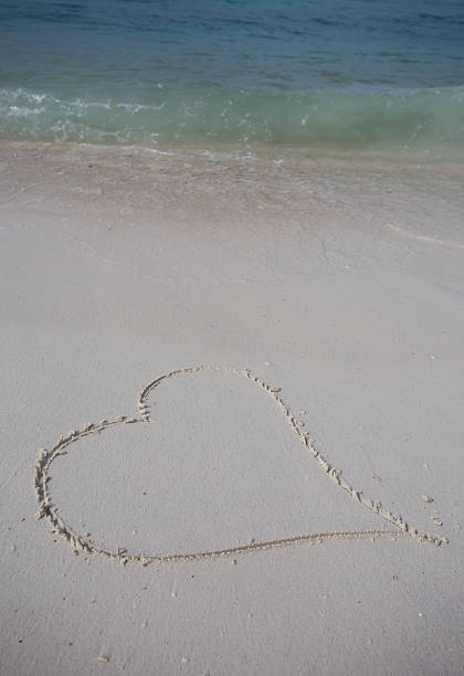 istock hearts drawn on the sand of a beach 464873862