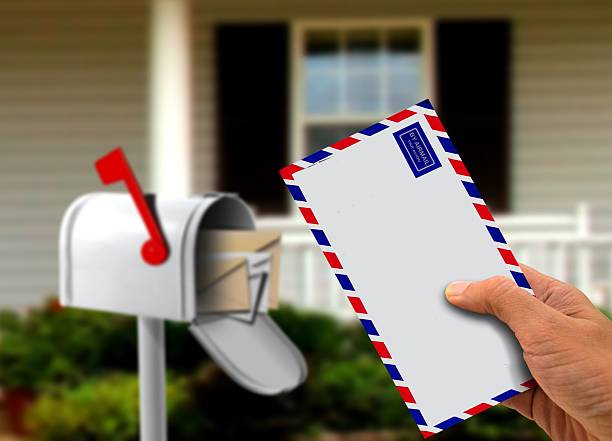 istock Hand Holding Envelope in Front of a House 464878421