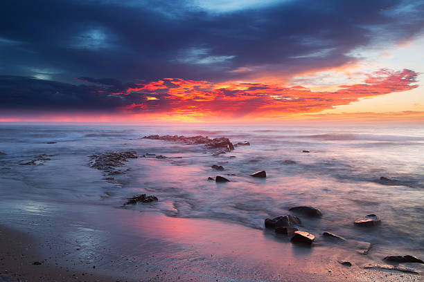 istock Sunrise over the ocean with rocks and water in foreground 464885913
