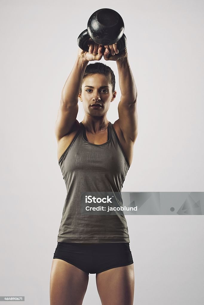 Mujer haciendo ejercicios con tetera bell - Foto de stock de Entrenamiento combinado libre de derechos