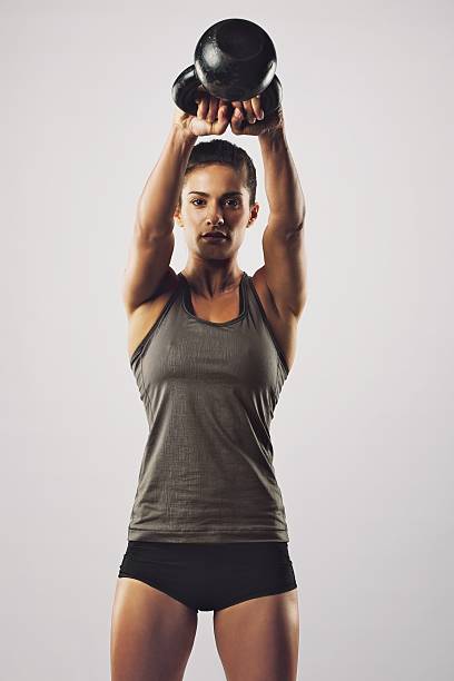 Young female doing swing exercise with a kettle bell. Fitness woman