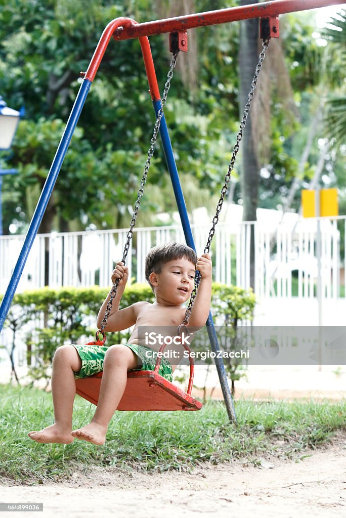 Boy swinging on playground swing. 2-3 Years Stock Photo