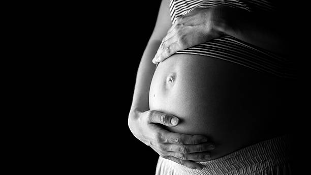 istock Pregnant belly over black background 464902238