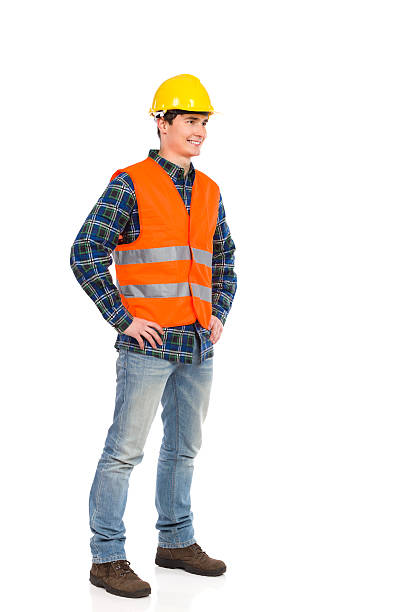 standing bauarbeiter im gelben helm und orange weste. - construction worker building contractor craftsperson full length stock-fotos und bilder