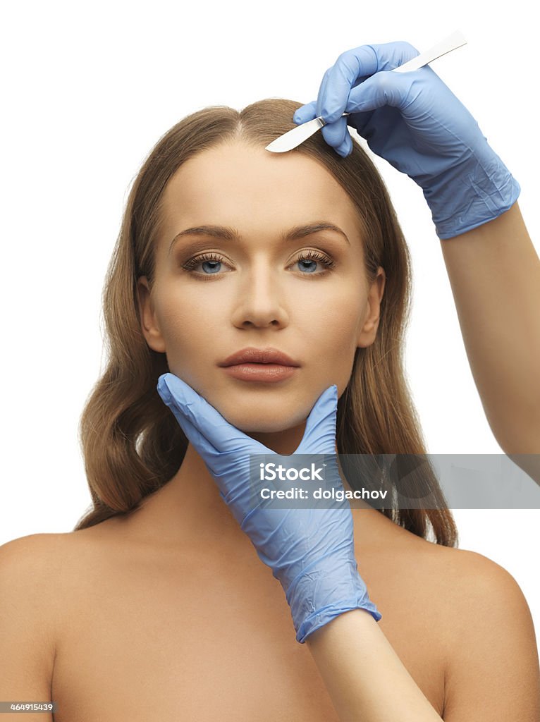 Woman receiving a face treatment at a beauty center people, beauty, plastic surgery and medicine concept - woman face and surgeon hands with scalpel  Blue Stock Photo