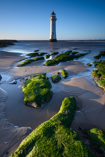 New Brighton lighthouse in Wirral, Merseyside with rock in foreground in low tide day