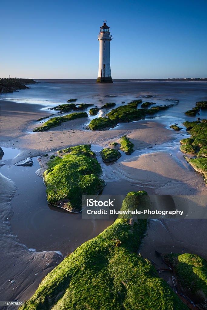 New Brighton lighthouse with green rocks foreground New Brighton lighthouse in Wirral, Merseyside with rock in foreground in low tide day The Wirral Stock Photo