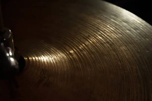 Brass cymbal texture with light shading on dark room.