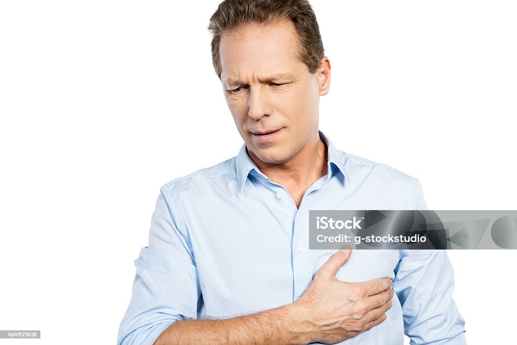 Pain in heart. Frustrated mature man holding hand on heart and expressing negativity while standing against white background 2015 Stock Photo