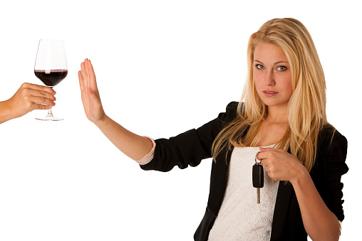 beautiful blond woman gesturing don't drink and drive gesture, with refusing a glass of red wine isolated over white