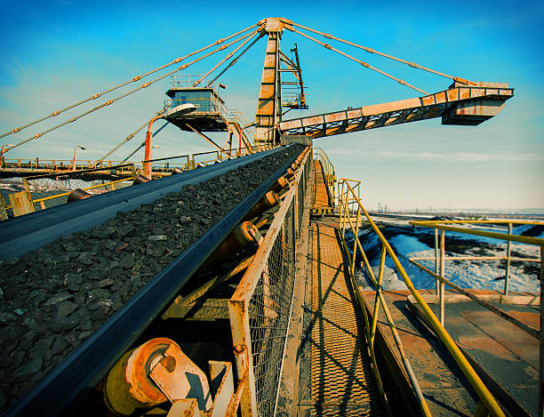 Close-up of a conveyor by the water conveyor transport for loading iron ore from the warehouse metal ore stock pictures, royalty-free photos & images
