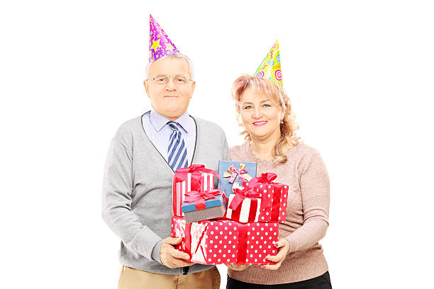 istock Happy mature couple with birthday hats holding presents 464934603