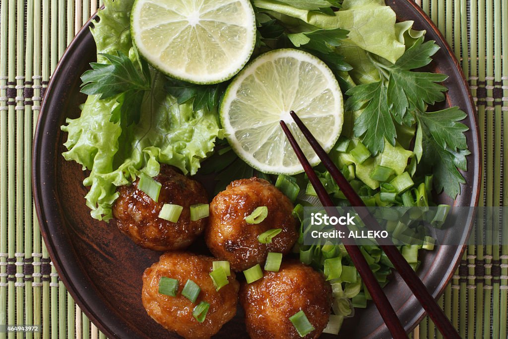 fish balls in curry sauce with lime top view fish balls in curry sauce with lime and fresh herbs and chopsticks on a bamboo table close-up. horizontal view from above 2015 Stock Photo