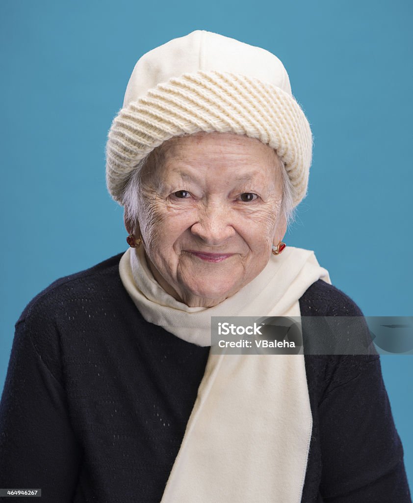 Old woman Portrait of old woman in hat on a blue background Active Seniors Stock Photo