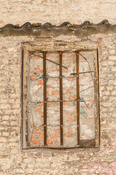 A bricked up window with rusted bars