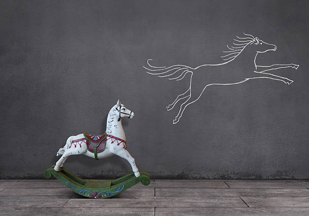 Dream of Rocking Horse Side view of wooden rocking horse on wooden floor with running (or jumping) horse sketched (chalk drawing) on the wall. concepts topics stock pictures, royalty-free photos & images