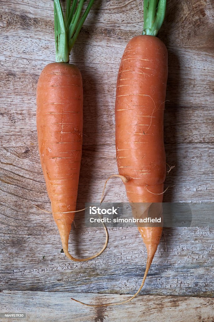 Two Organic Carrots On A Chopping Board Two organic carrots on a wooden chopping board. 2015 Stock Photo