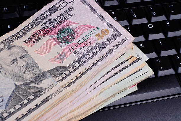 US currency laying on a computer keyboard stock photo