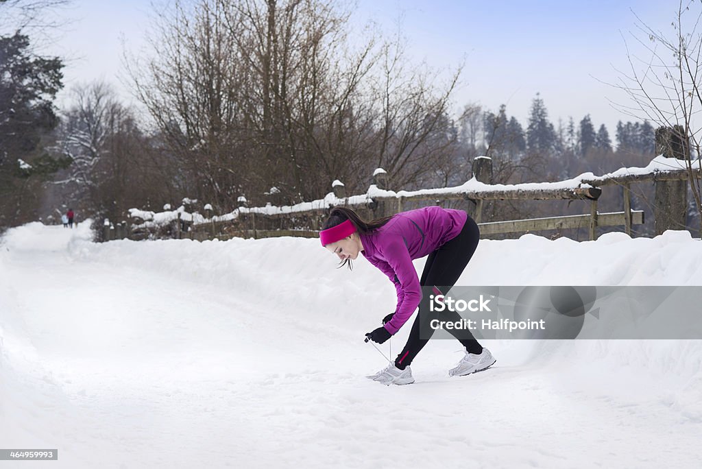 Woman running in winter Athlete woman is running during winter training outside in cold snow weather. Active Lifestyle Stock Photo