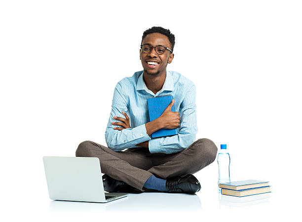 szczęśliwy african american college student siedzi z laptopa na biały - sitting young men book isolated on white zdjęcia i obrazy z banku zdjęć