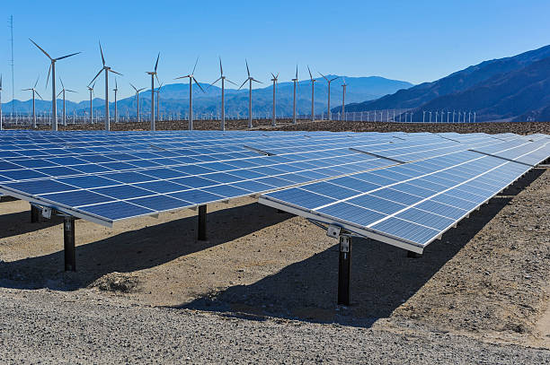 Solar panels in front of wind turbines and mountians stock photo