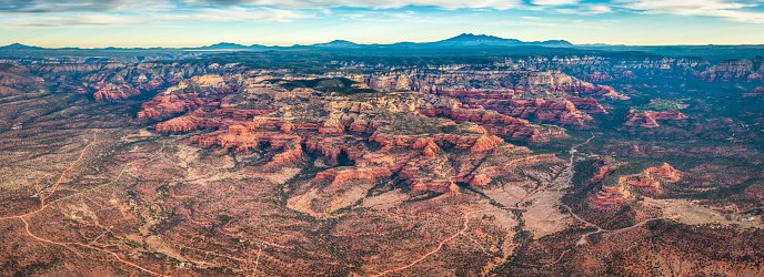 First light of daybreak illuminating the dramatic red rock landscape, mountains, buttes and mesas of Sedona, an aerial panorama from high above this popular recreation and vacation area in Arizona, Southwest USA. ProPhoto RGB profile for maximum color fidelity and gamut.
