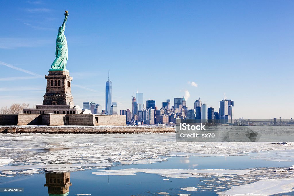 Statue of Liberty NYC Skyline Frozen Hudson River Brooklyn Bridge Ice sheets form around Statue of Liberty and NYC. One World Trade Center. Brooklyn Bridge, right. Hudson river freezes over from arctic weather. New York City Stock Photo