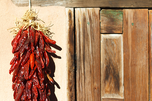 Santa Fe style: A chile pepper ristra hangs on an adobe wall next to an old wooden (mesquite) door. 