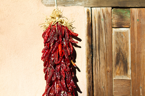 Santa Fe style: A chile pepper ristra hangs on an adobe wall next to an old wooden (mesquite) door. Copy space available.