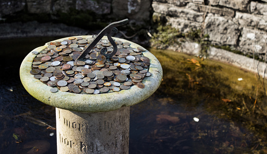 Sundial in wishing well with money