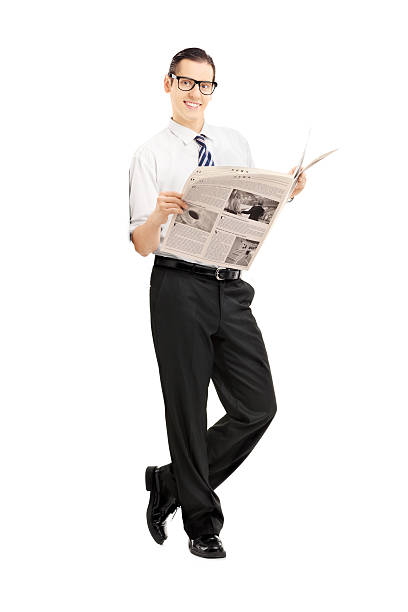 istock Smiling businessman leaning against wall and holding a newspaper 464973719