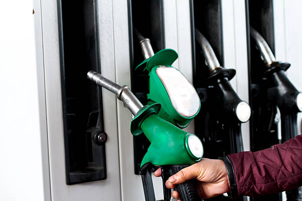 Fuel Pumps at Petrol Station Person lifting fuel pump to fill fuel in car  fuel prices photos stock pictures, royalty-free photos & images