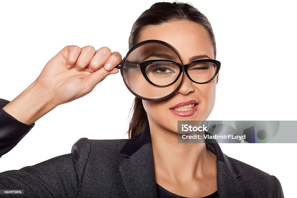 Smiling young woman looking through a magnifying glass smiling young woman looking through a magnifying glass 2015 Stock Photo