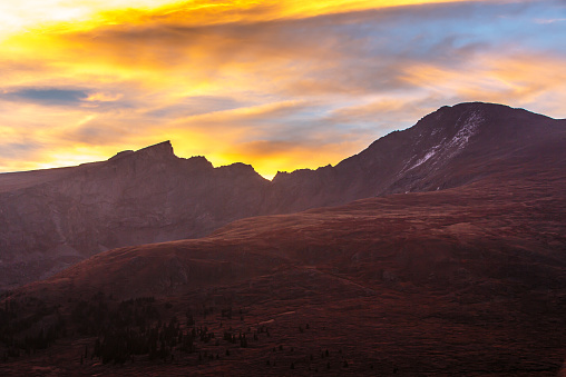 The Fall sunrise paints the sky behind Colorado 14'er Mount Bierstadt and the Sawtooths. Gold, blue, and silver colors explode in this image from Guanella Pass in Georgetown, Colorado.