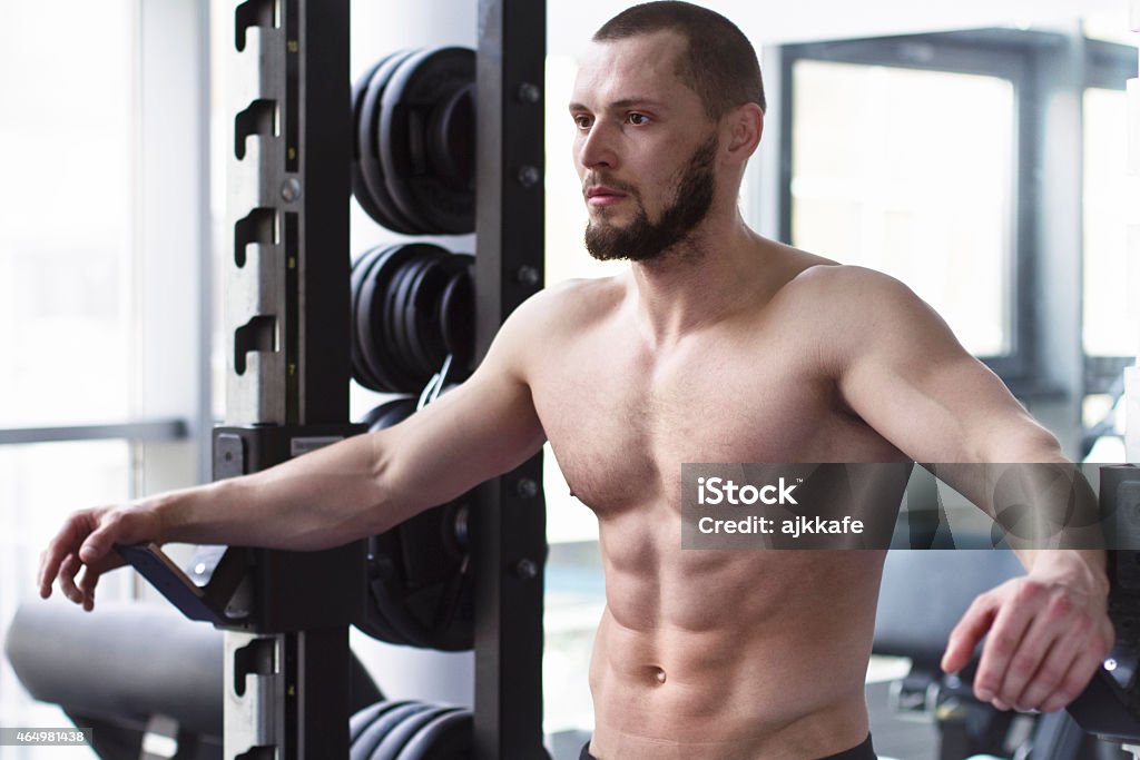 Male bodybuilder at gym Attractive shirtless male bodybuilder posing at the gym. 2015 Stock Photo