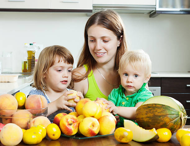 istock Ordinary woman with  daughters eating fruits 464982453