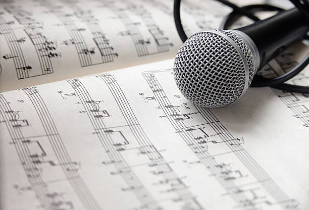 istock Microphone and cable lying on sheet of music 464999456