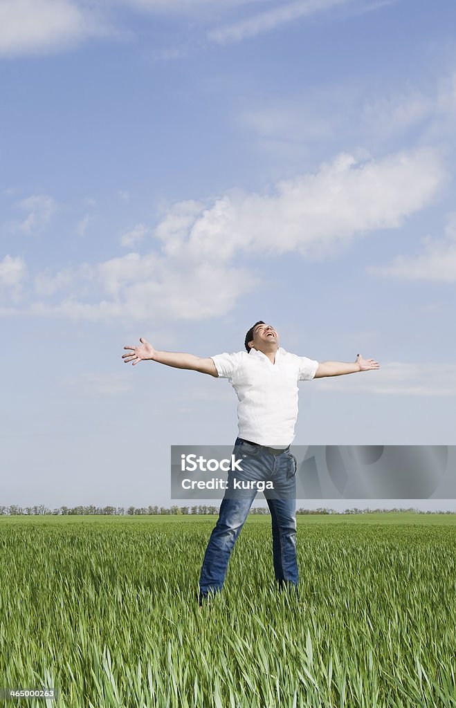 young man moves in a green field of grass young man moves in a green field of grass to meet the sun Activity Stock Photo