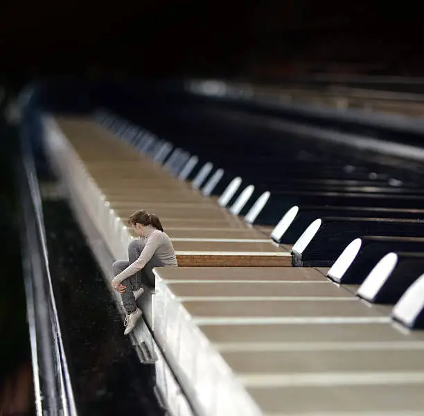 Photo of Young woman sitting on a piano key