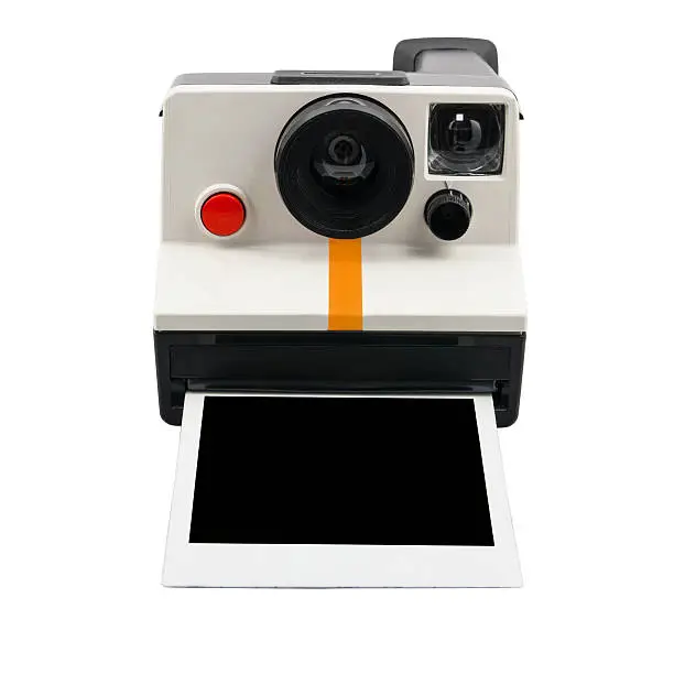 Old style instant camera with blank photograph coming out, isolated on a white background.