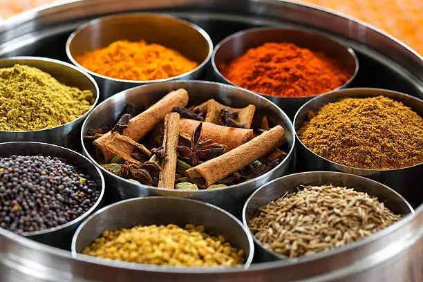 Whole and ground spices neatly organized in a metal tin.