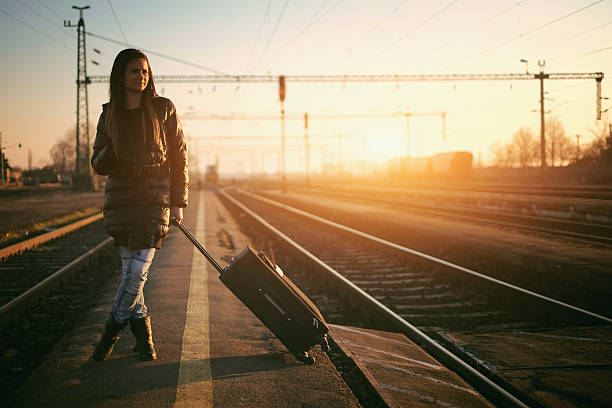 istock Young woman standing on railroad tracks with suitcase 465031572