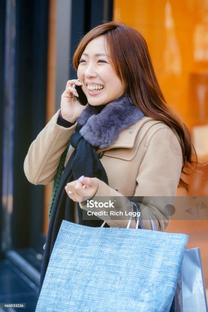 Japanese Woman in Ginza Tokyo A young Japanese woman talks on a smartphone on a sidewalk in the Ginza area of Tokyo, Japan. 20-29 Years Stock Photo