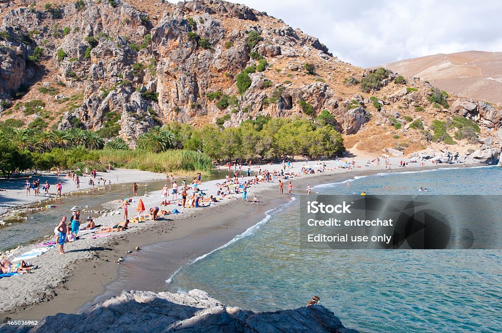 Tourists on the Preveli Beach on Crete, Greece. Crete, Greece - July 23, 2014: Holidaymakers sunbathe on the famous Preveli Beach with an exotic lagoon and the Kourtaliotis River.The beach can be reached by foot from the parking nearby the Preveli Monastery or by boats which leave from Plakias and Agia Galini. 2015 Stock Photo