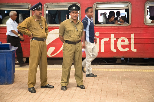 Colombo, Sri Lanka - March 12, 2014: Two policemen standing at the train station. The police force has a manpower of approximately 85,000.