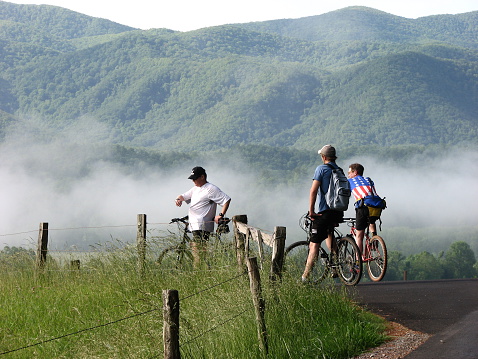 Gatlinburg, USA- May 25, 2010: Three men take a rest on bicycles with mountains in the background.